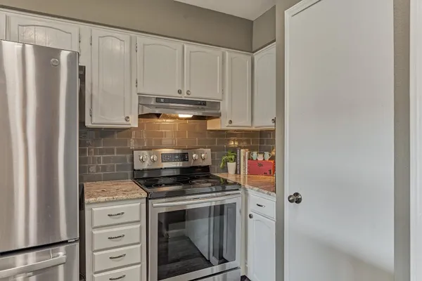 a kitchen with stainless steel appliances granite countertop a lot of counter space and wooden floors