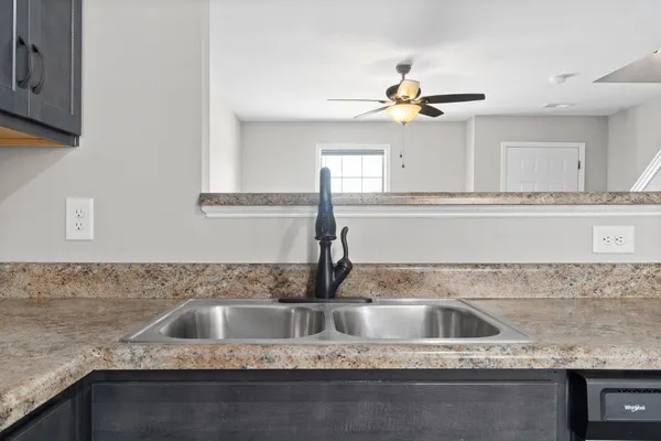 a kitchen with a sink granite counter tops and a view of living room
