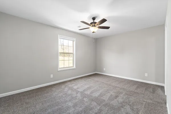 a view of an empty room with chandelier fan