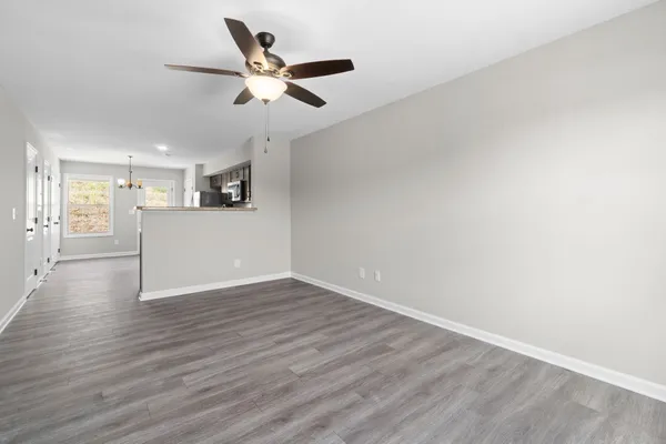 a view of an empty room with wooden floor and a ceiling fan