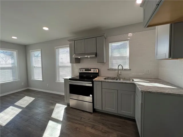 a kitchen with stainless steel appliances granite countertop a sink stove and cabinets
