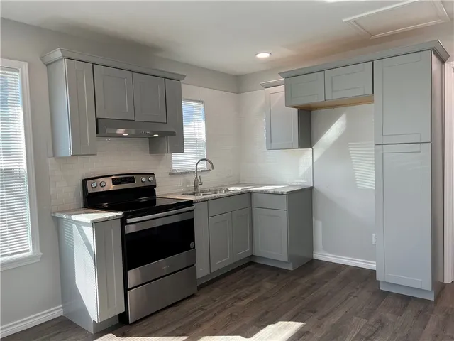 a kitchen with stainless steel appliances granite countertop white cabinets and a stove top oven