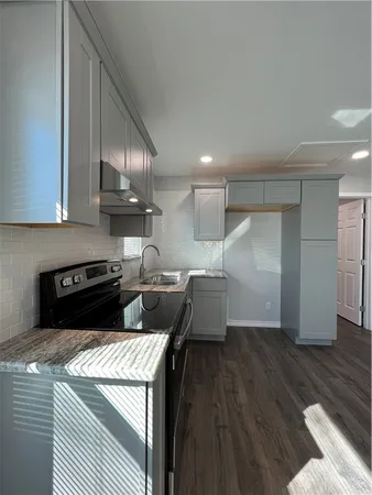 a kitchen with a stove a refrigerator and wooden floor