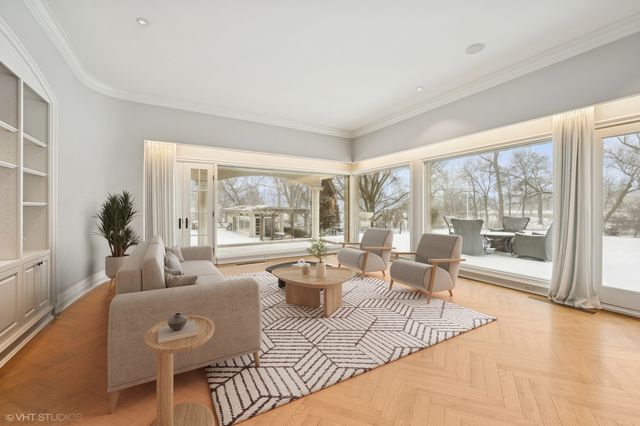 a living room with furniture large windows and wooden floor