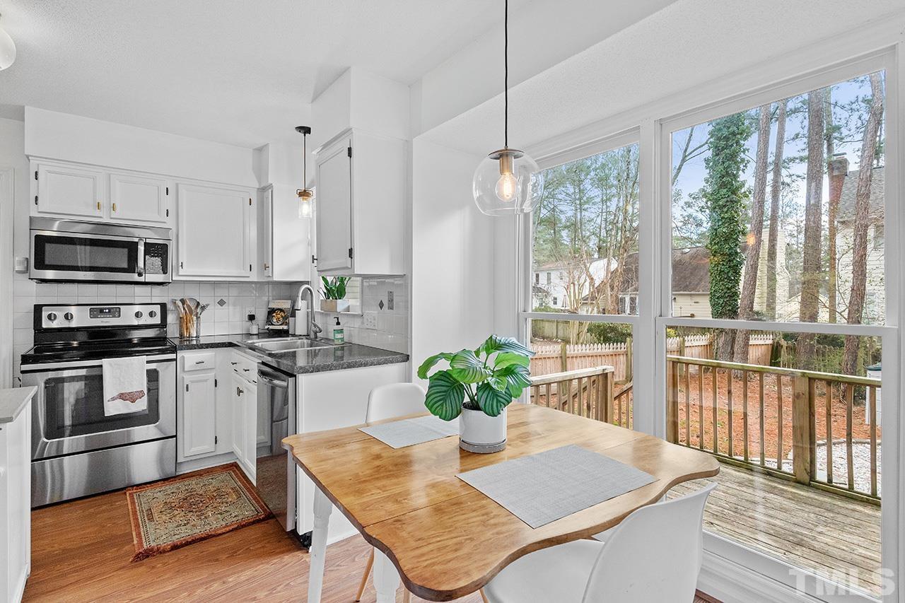 4428 Liverpool Lane Raleigh, NC 27604 - Photo 6 of 24 a kitchen with stainless steel appliances granite countertop a stove a refrigerator a sink a dining table and chairs with wooden floor