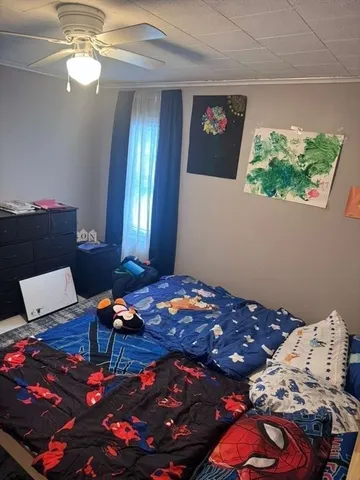 a bedroom with a bed window and lamp on dresser