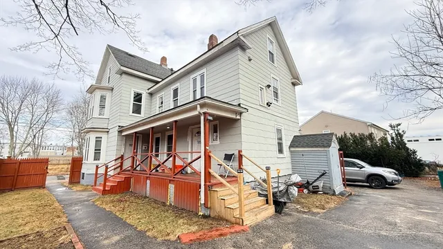 a view of a white house with large windows and a table and chairs