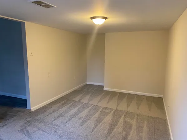 an empty room with wooden floor and mirror