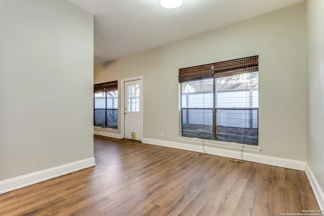 an empty room with wooden floor and windows