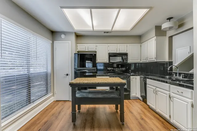 a kitchen with a wooden floor and white cabinets
