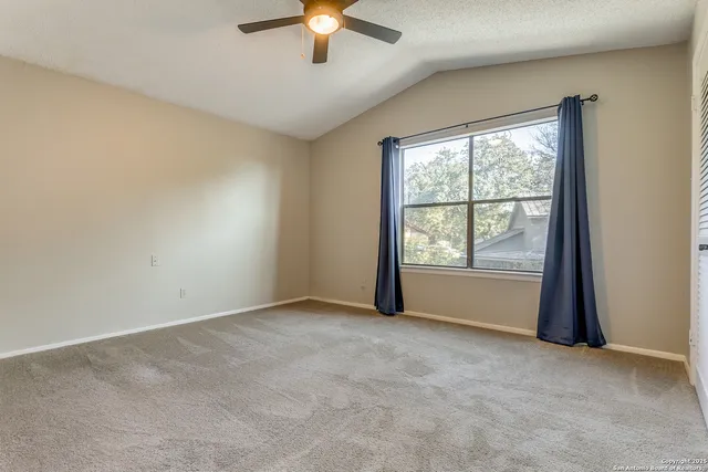 an empty room with chandelier fan and windows