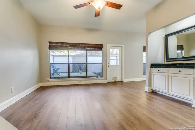 an empty room with wooden floor fan and windows