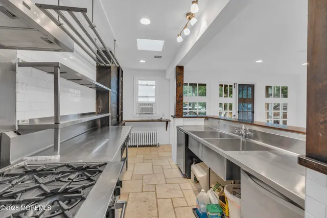 a large kitchen with kitchen island a large counter space a sink stainless steel appliances and cabinets