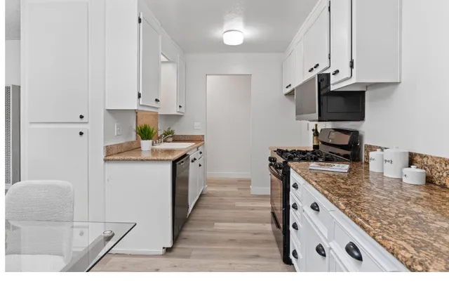 a kitchen with stainless steel appliances granite countertop a stove a sink and a microwave