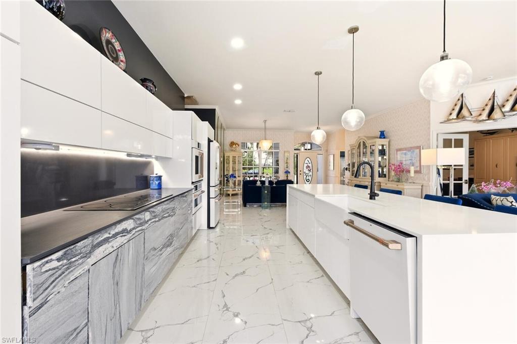 209 Countryside Drive Naples, FL 34104 - Photo 13 of 50 Two tone kitchen featuring modern cabinets, hanging light fixtures, white appliances, wallpapered walls, and two tone cabinets
