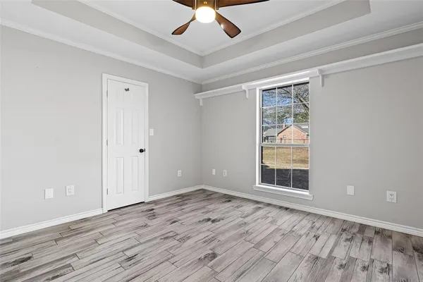 an empty room with wooden floor chandelier fan and windows