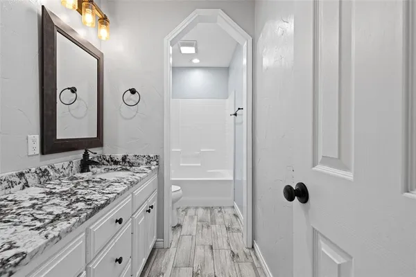 a bathroom with a granite countertop sink a mirror and shower