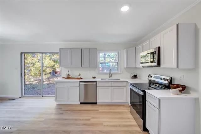 a kitchen with stainless steel appliances granite countertop a stove top oven a sink dishwasher and a refrigerator with wooden floor