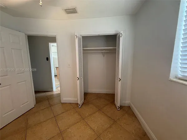 a view of an empty room with closet and a window
