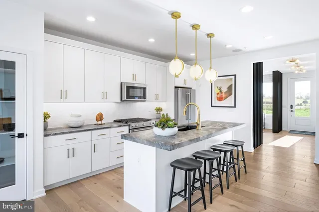 a kitchen with kitchen island granite countertop a stove a sink a dining table and chairs with wooden floor