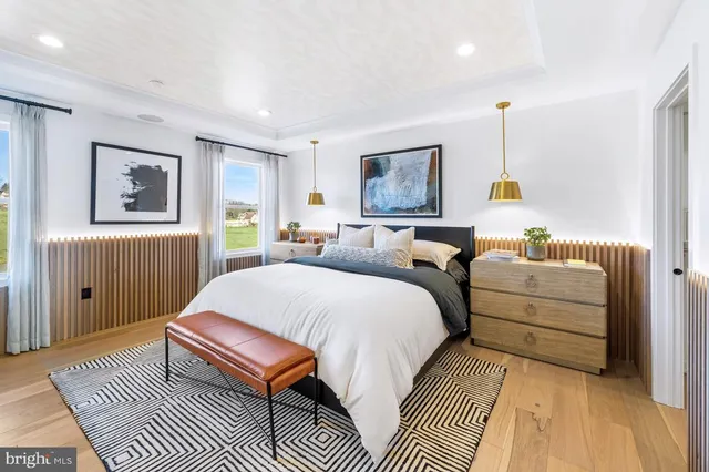 a spacious bedroom with a bed a rug and paintings on the wall