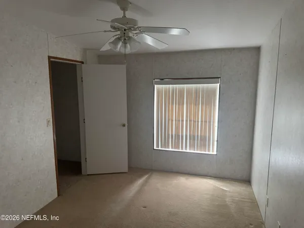 an empty room with chandelier fan and windows