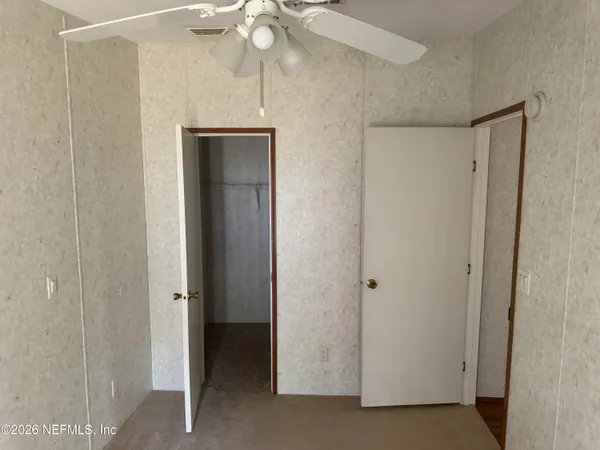 a view of an empty room with a chandelier fan