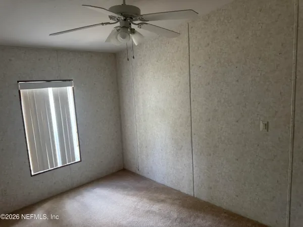 an empty room with windows and fan