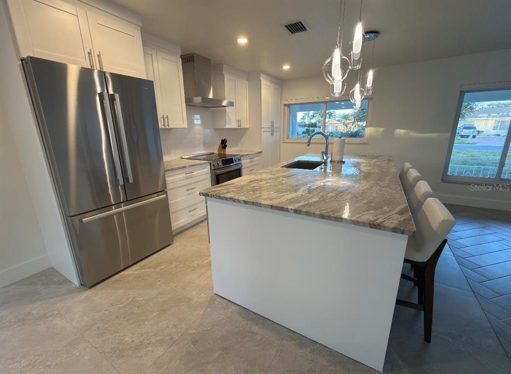 12350 4th Street East Treasure Island, FL 33706 - Photo 4 of 16 a kitchen with stainless steel appliances granite countertop a refrigerator a sink a stove a microwave a island and a refrigerator