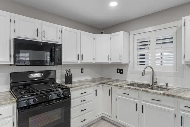 a kitchen with granite countertop white cabinets and appliances