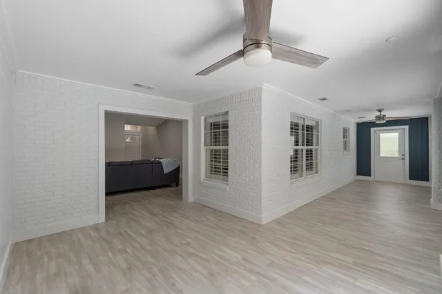 a view of an empty room with a window and wooden floor