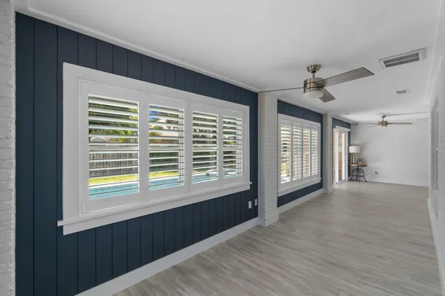 a view of an empty room with a window and wooden floor