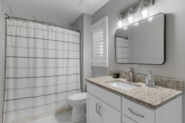 a bathroom with a granite countertop sink a toilet and a mirror