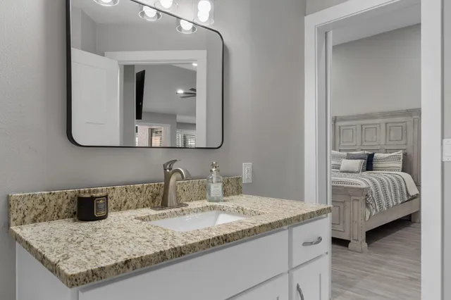 a en suite bathroom with a granite countertop sink and mirror