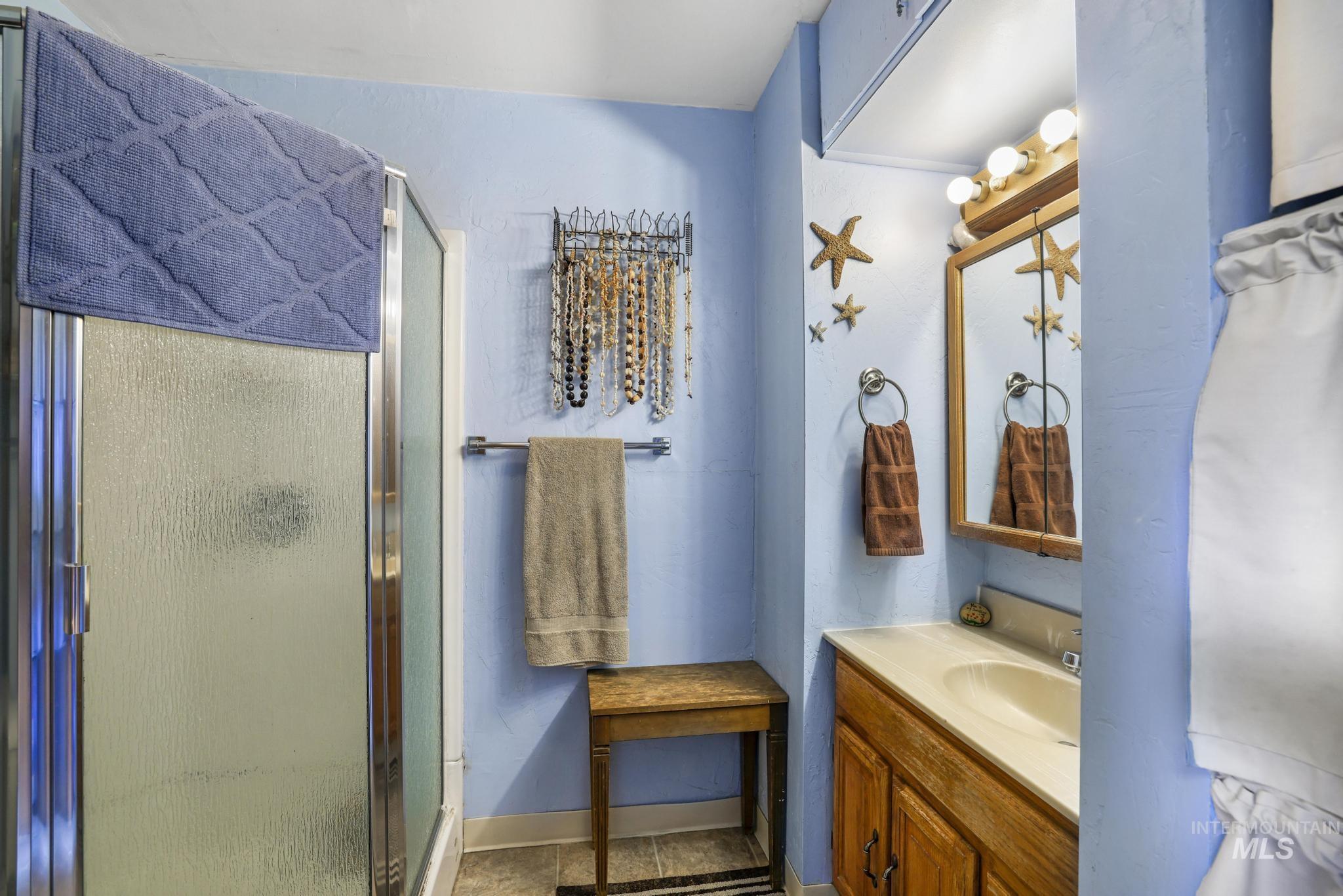 19591 Queen Crown Road Carey, ID 83320 - Photo 11 of 37 Bathroom featuring a glass-enclosed shower, wood-finish vanity with an integrated sink, wall-mounted mirror, and vanity lighting