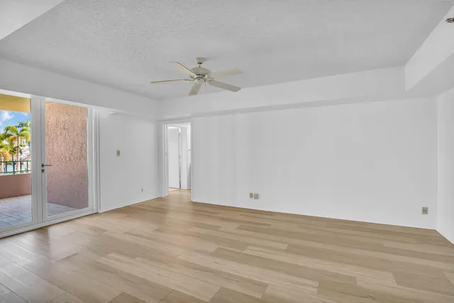 an empty room with wooden floor ceiling fan and windows