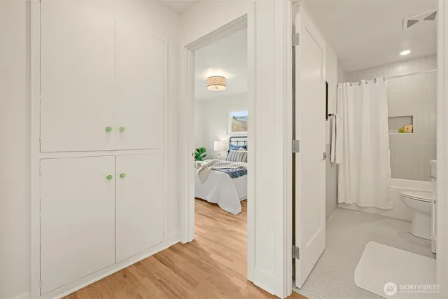 a view of a hallway with bathroom and wooden floor