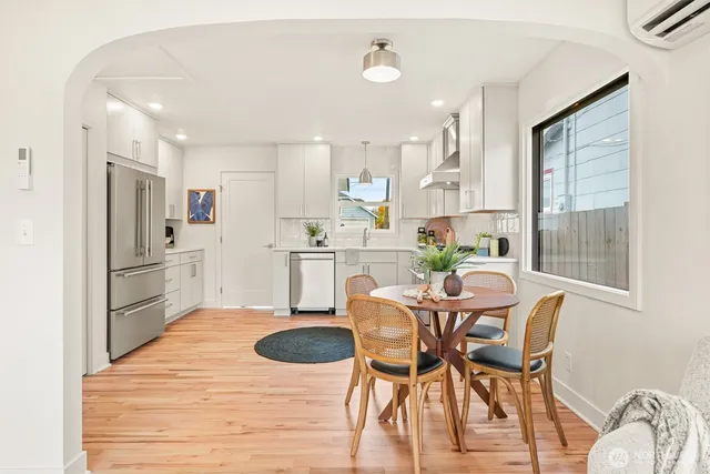 a kitchen with stainless steel appliances kitchen island granite countertop a dining table chairs and a refrigerator