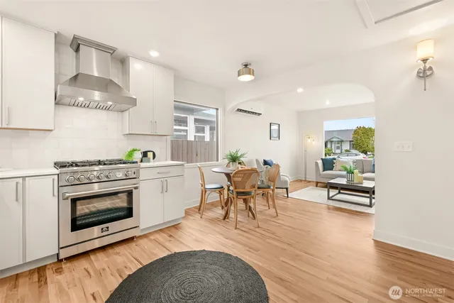 a kitchen with stainless steel appliances a stove a sink dishwasher and white cabinets with wooden floor