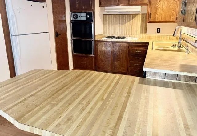 a kitchen with granite countertop a refrigerator a stove and a sink with wooden floor