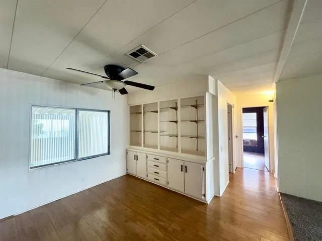 a view of empty room with wooden floor and fan