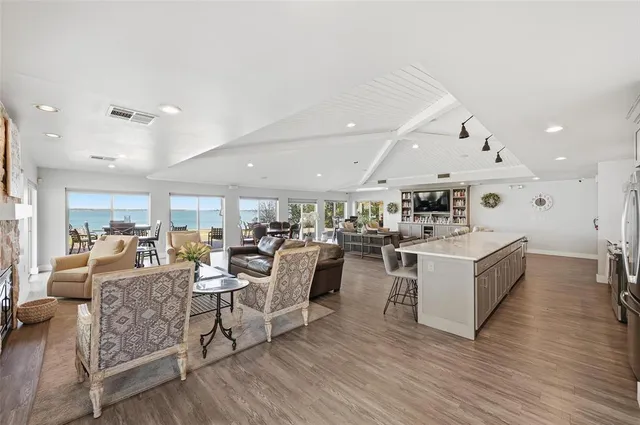 a living room with lots of furniture kitchen view and a wooden floor