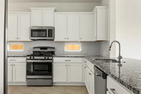 a kitchen with granite countertop white cabinets and stainless steel appliances