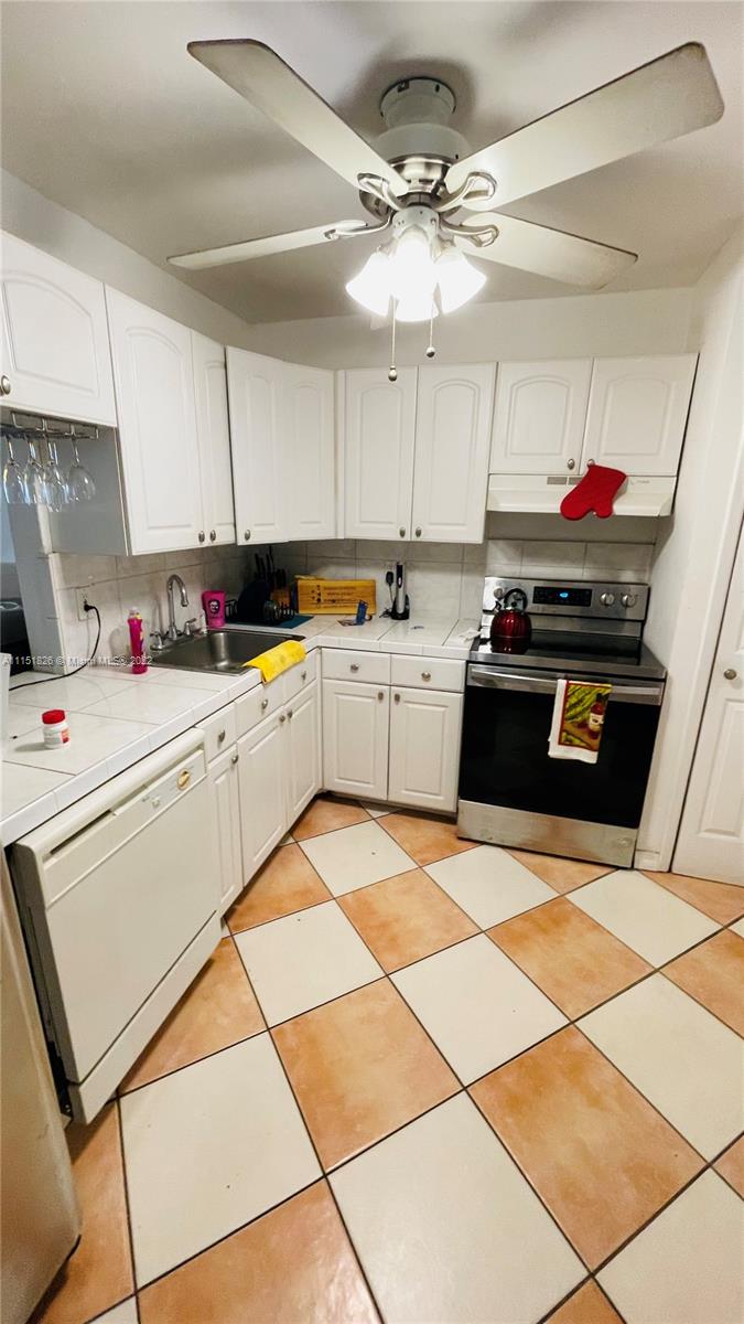 Second Forum Condominium North Miami Beach, FL 33179 - Photo 5 of 12 a kitchen with a sink a stove and white cabinets