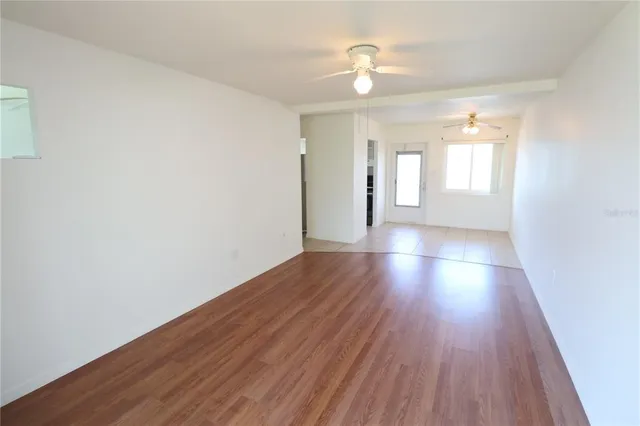 a view of an empty room with wooden floor and a window