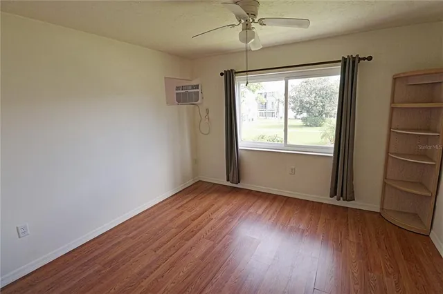 an empty room with wooden floor fan and windows