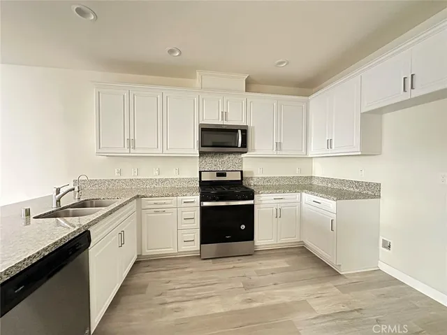 a kitchen with granite countertop white cabinets and stainless steel appliances
