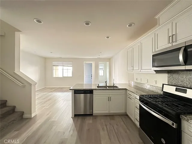 a kitchen with stainless steel appliances kitchen island granite countertop a sink cabinets and wooden floor