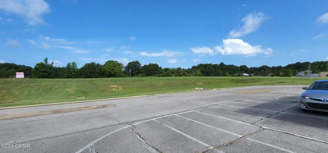a view of a field with an trees in the background