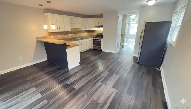 a kitchen with stainless steel appliances granite countertop a refrigerator a sink dishwasher a stove and white countertops with wooden floor